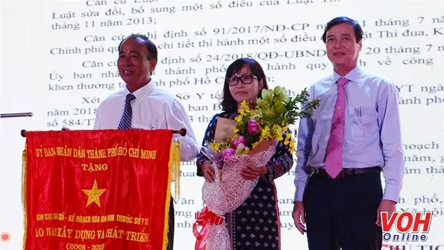 Bác sĩ Trần Văn Trị - Chi cục trưởng Chi cục Dân số - Kế hoạch hóa gia đình TP đón nhận Cờ truyền thống của UBND TP