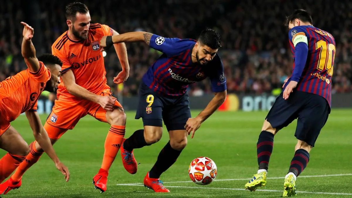 Tiền đạo Suarez của Barcelona đi bóng trước sự áp sát của cầu thủ Lyon trong trận lượt về vòng 1/8 Champions League 2019.