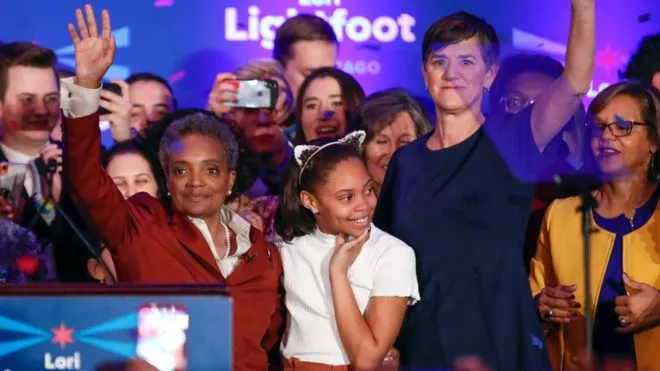 Bà Lori Lightfoot (trái) lên sân khấu mừng chiến thắng với vợ và con gái (Ảnh: BBC)