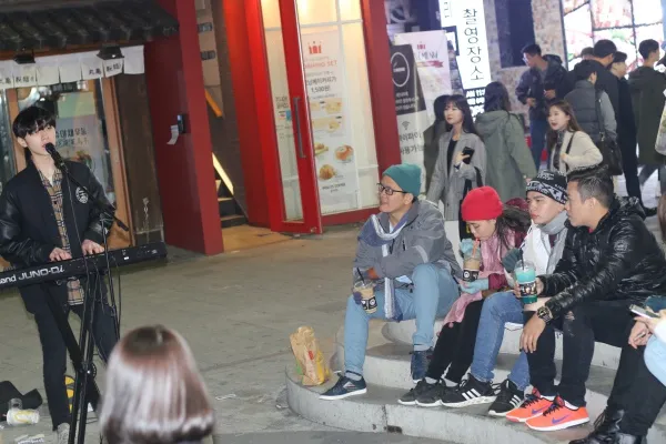 Du khách xem biểu diễn âm nhạc đường phố tại một khu chợ đêm ở Hàn Quốc. 