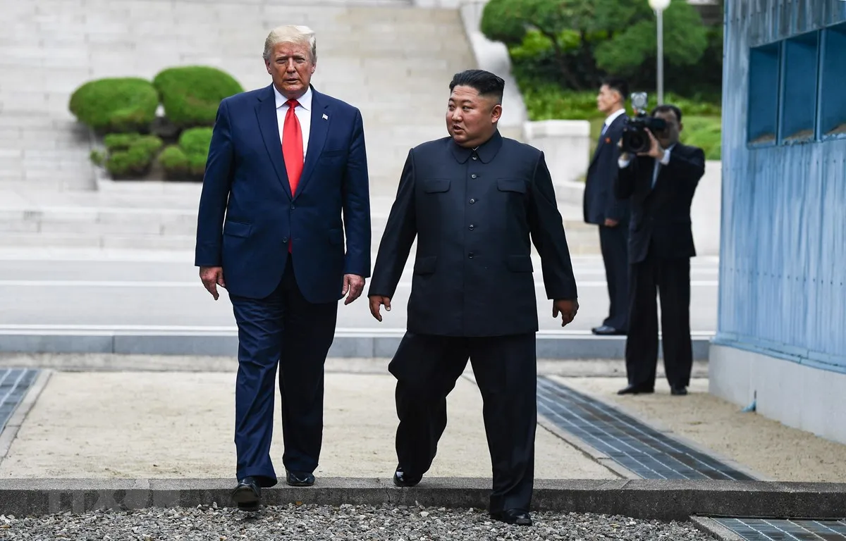 Tổng thống Mỹ Donald Trump (trái) và nhà lãnh đạo Triều Tiên Kim Jong-un bước chân qua đường ranh giới phân chia hai miền Triều Tiên tại DMZ, sang phần lãnh thổ của Triều Tiên chiều 30/6/2019. (Nguồn: AFP/TTXVN)