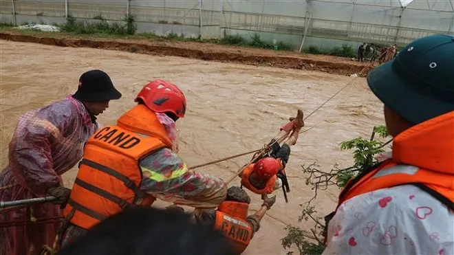 Người dân bị mắc kẹt ở xã Lát (huyện Lạc Dương,Lâm Đồng) đu dây qua dòng nước lũ nhờ sự hỗ trợ của lực lượng cứu hộ