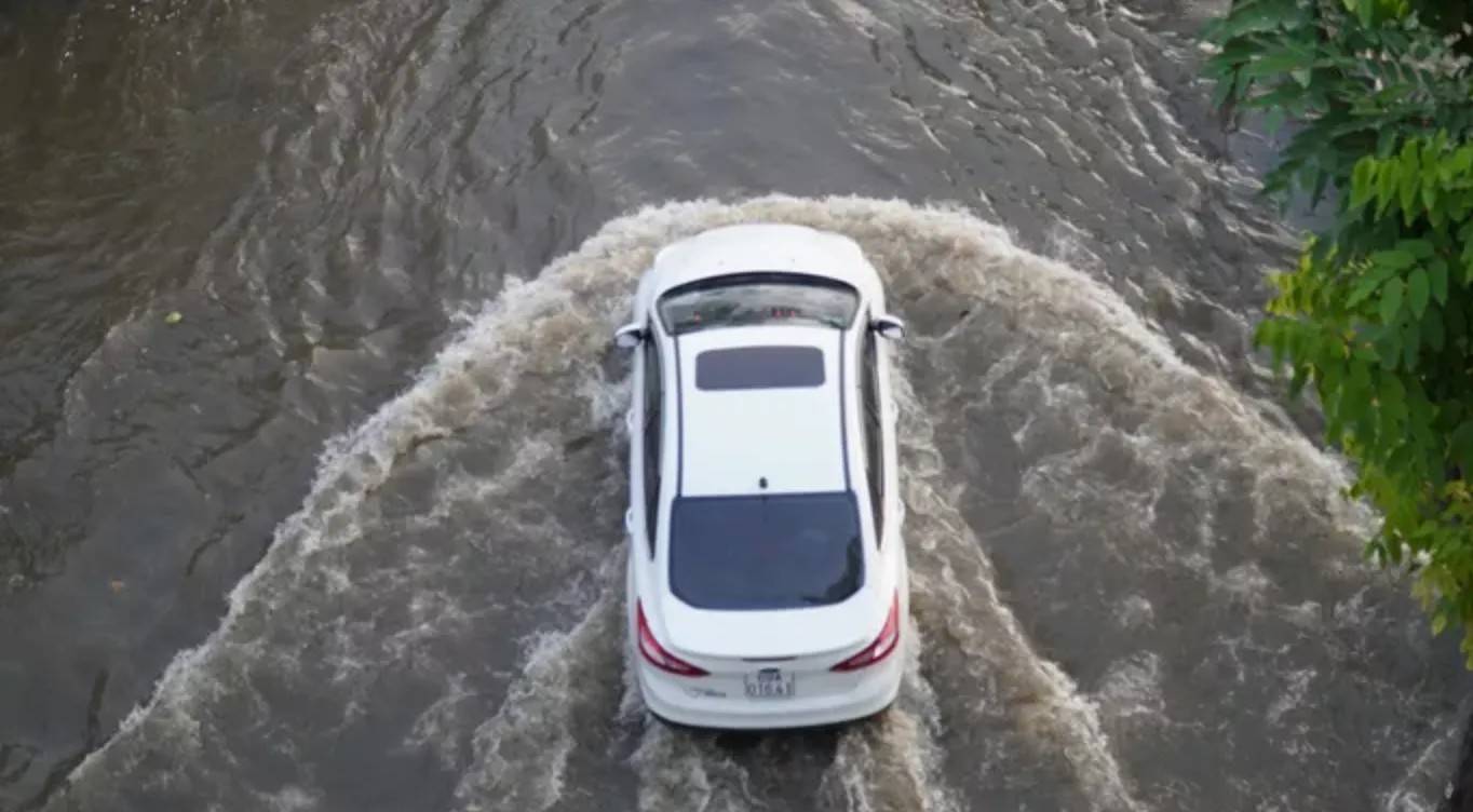 Xe ô tô di chuyển trên mặt nước tạo thành những đợt sóng cao. Ảnh: NLD