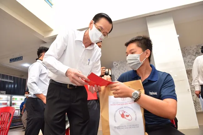 Phó Chủ tịch Thường trực UBND TP Lê Thanh Liêm trao quà và phiếu hiếu máu cho người tham gia hiến máu tình nguyện.