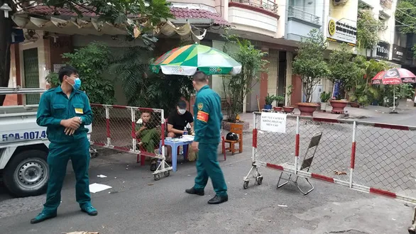 Lực lượng chức năng lập hàng rào cách ly và canh gác khu vực chung cư nơi bệnh nhân 92 đang ở - Ảnh: CHÂU TUẤN - TTO