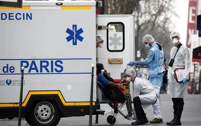 Nhân viên cấp cứu di chuyển bệnh nhân bị nghi mắc Covid-19 từ nhà đến bệnh viện ở Paris, ngày 20-3. 
