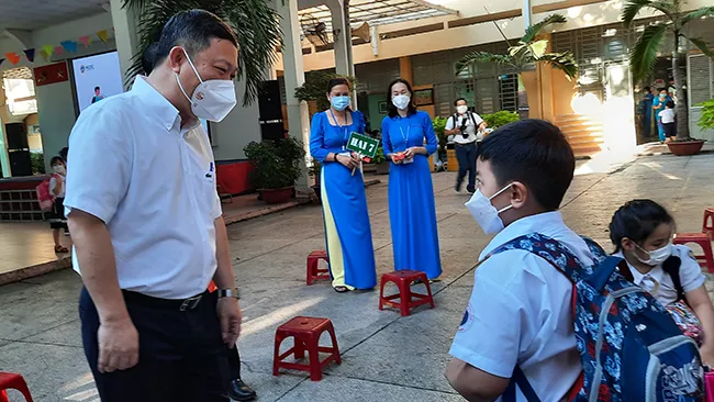  Phó Chủ tịch UBND Thành phố Dương Anh Đức trò chuyện cùng một  học sinh trường tiểu học Nguyễn Đình Chiểu về việc  đi học trở lại
