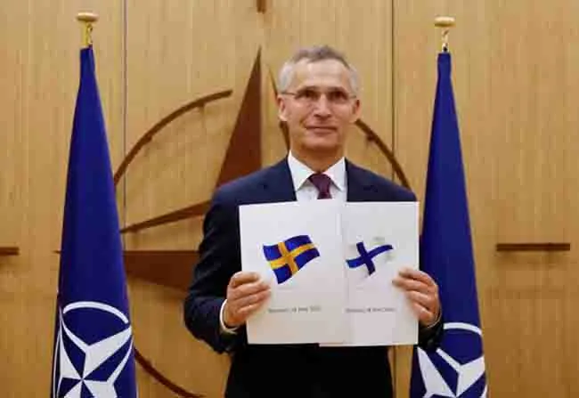 Tổng thư ký NATO Jens Stoltenberg giơ hai bìa màu trắng là đơn xin gia nhập của Phần Lan và Thụy Điển ngày 18/5. (Ảnh: Reuters)
