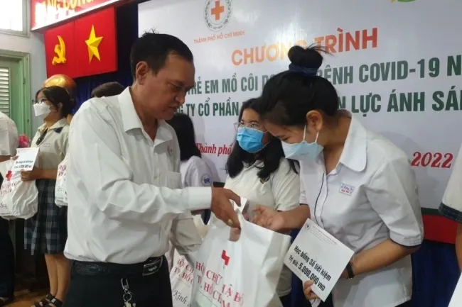 H1 Ông Trần Trường Sơn – Chủ tịch Hội Chữ thập đỏ Thành phố Hồ Chí Minh trao học bổng và quà tặng đến các em học sinh mồ côi do Covid-19.