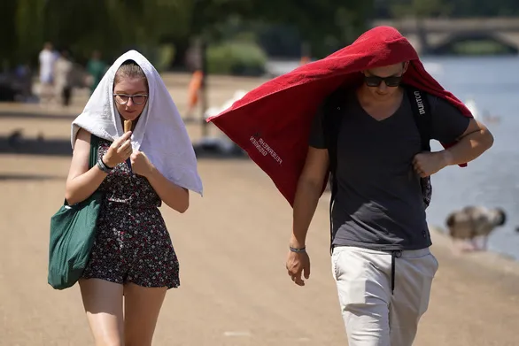 Người dân đi dưới nắng nóng đổ lửa ở tây London ngày 19-7 - Ảnh: AFP