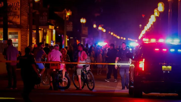 Những người đi biển xuất hiện cạnh các nhân viên thực thi pháp luật tại hiện trường vụ xả súng ở thành phố Hollywood, bang Florida, Mỹ tối 29/5 - Ảnh: ABC/GETTY