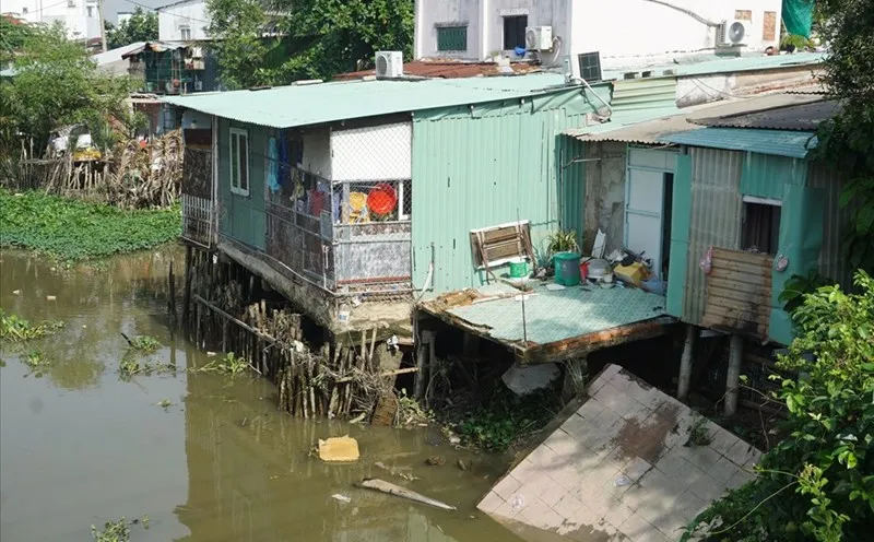 Một phần căn nhà sát cầu Giồng Ông Tố (thành phố Thủ Đức) bị sạt lở xuống rạch. Ảnh: LĐ