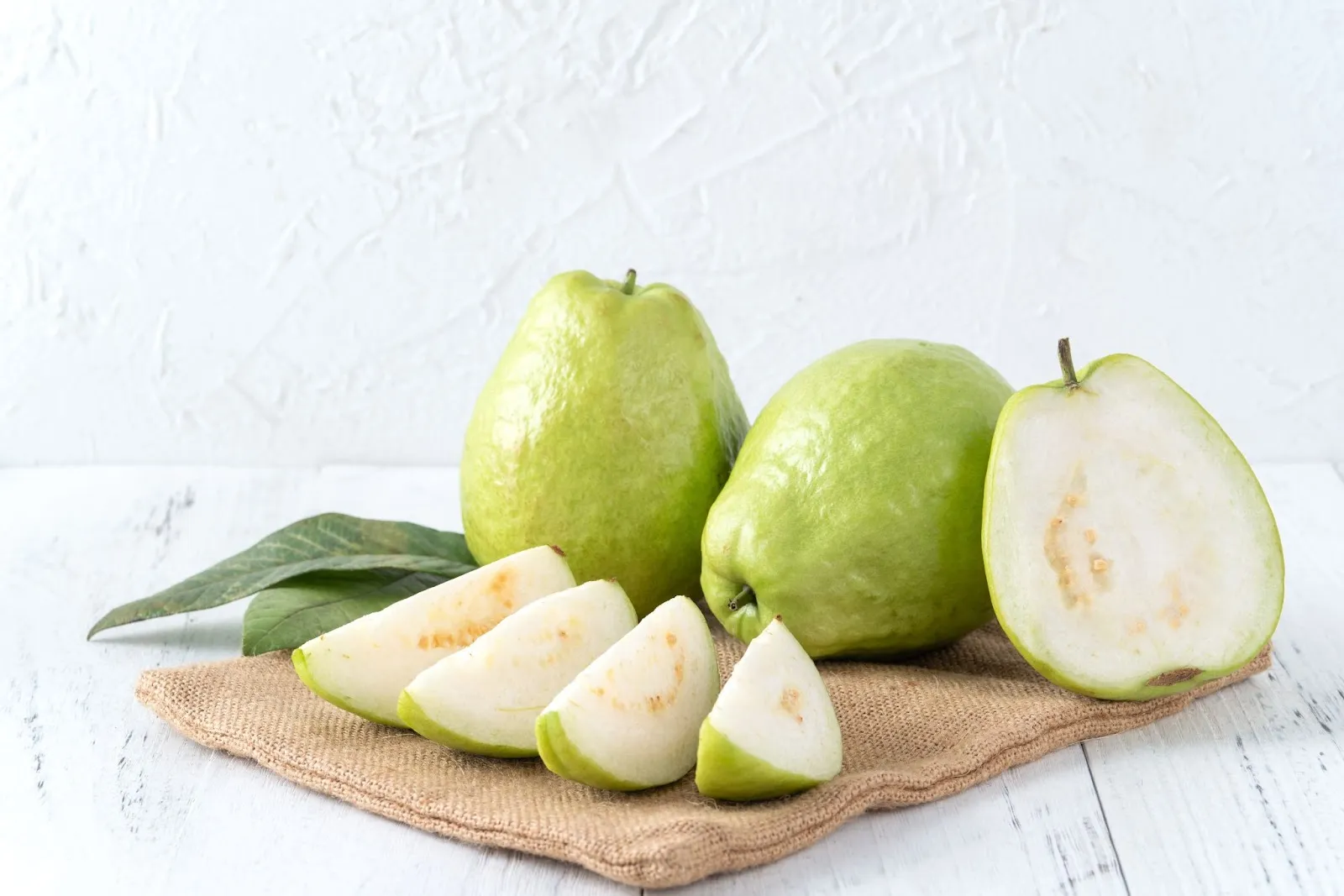 delicious-beautiful-guava-set-with-fresh-leaves-isolated-bright-white-wooden-table-background-close-up