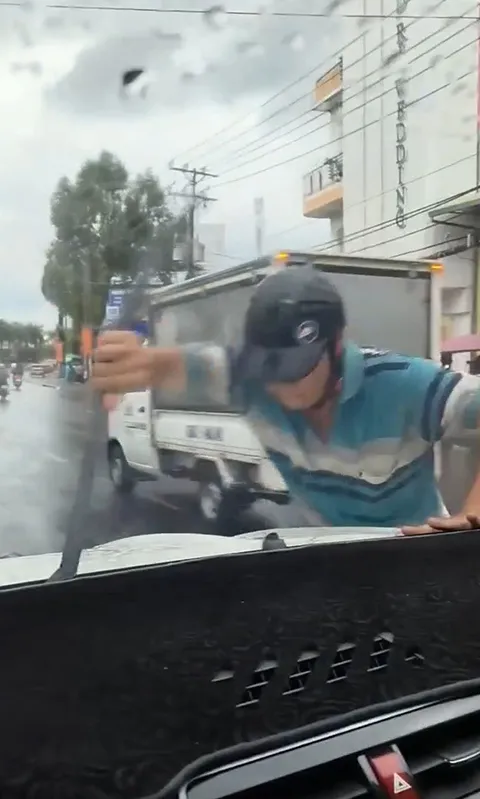 Người đàn ông bẻ cây gạt nước của xe ô tô
