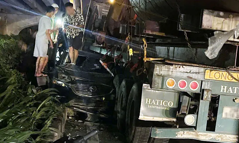 Chiế ô tô con biến dạng sau khi bị kẹp giữa xe đầu kéo và dải phân cách