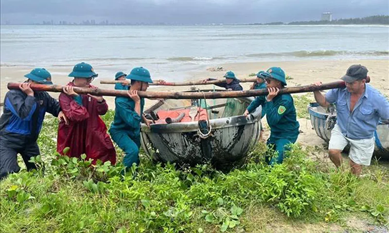 Lực lượng chức năng phường Hải Vân giúp ngư dân đưa thuyền thúng lên bờ tránh bão. Ảnh TTXVN