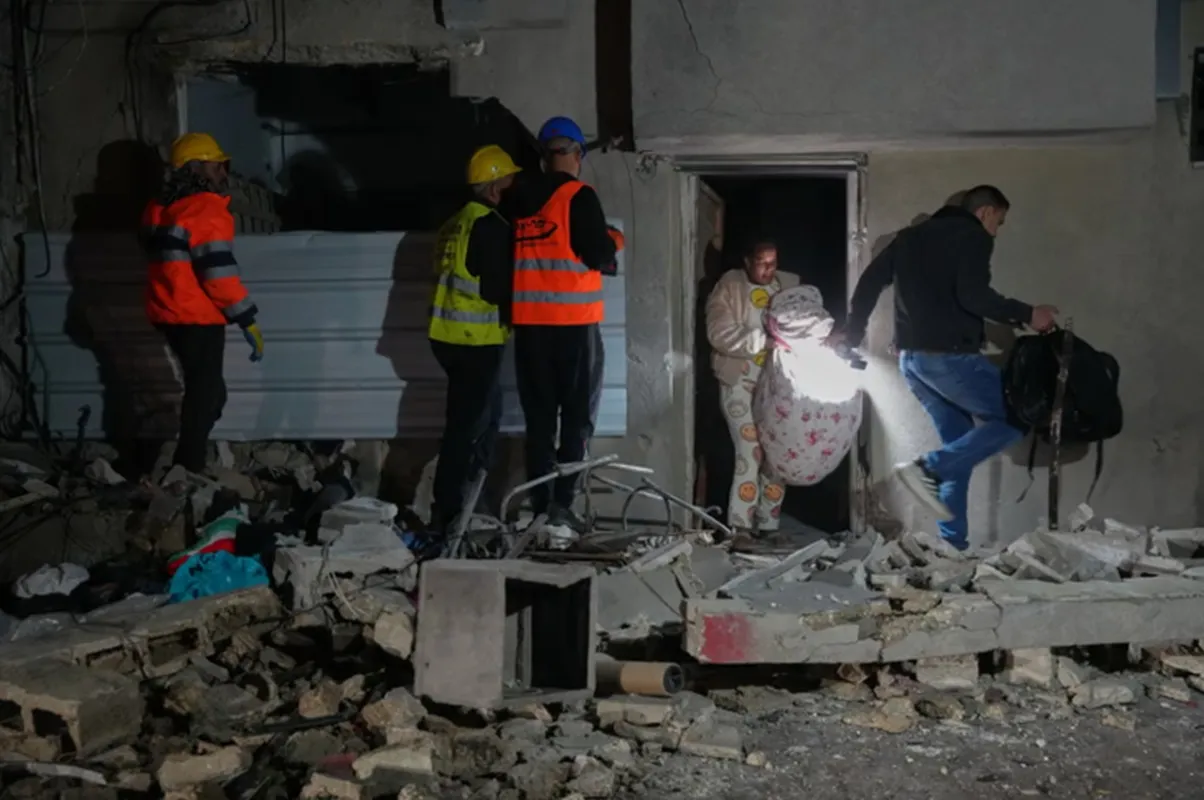 Người dân rời khỏi một tòa nhà bị hư hại sau một vụ tấn công tên lửa ở Tel Aviv, Israel, sáng sớm 28-3 - Ảnh AP