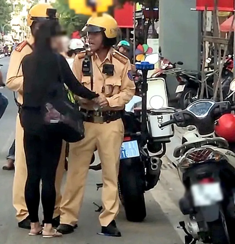 Cán bộ Đội Cảnh sát giao thông Bàn Cờ cố gắng lấy lại 2 tờ biên bản từ tay cô gái - Ảnh cắt từ clip lan truyền trên mạng xã hội