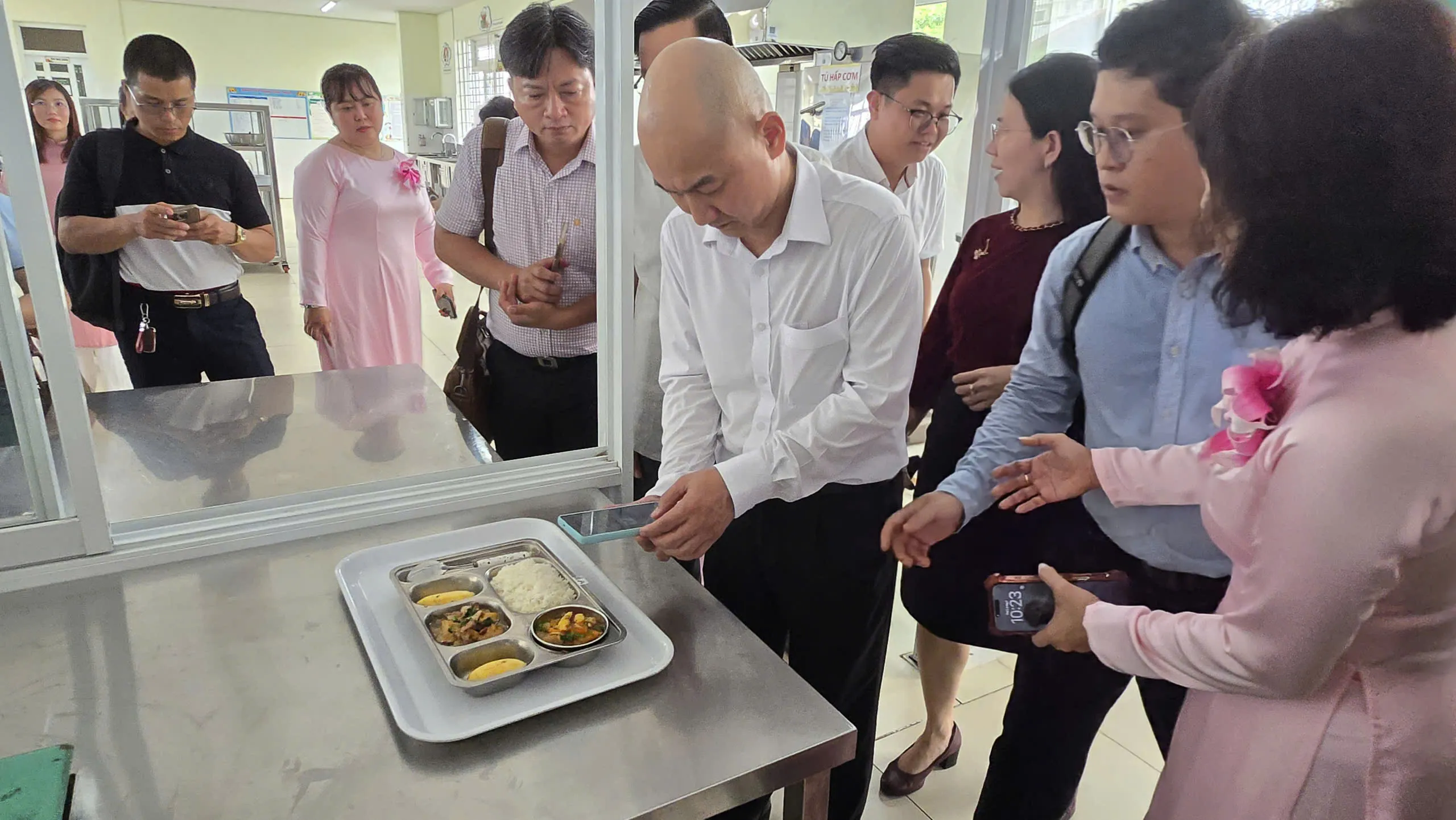 Ông Nguyễn Nguyên Phương - Phó Giám đốc Sở Công Thương Thành phố dùng điện thoại đi quét mã QR tick xanh trên suất ăn của Trường mầm non Phú Mỹ. Ảnh - Bá Nam