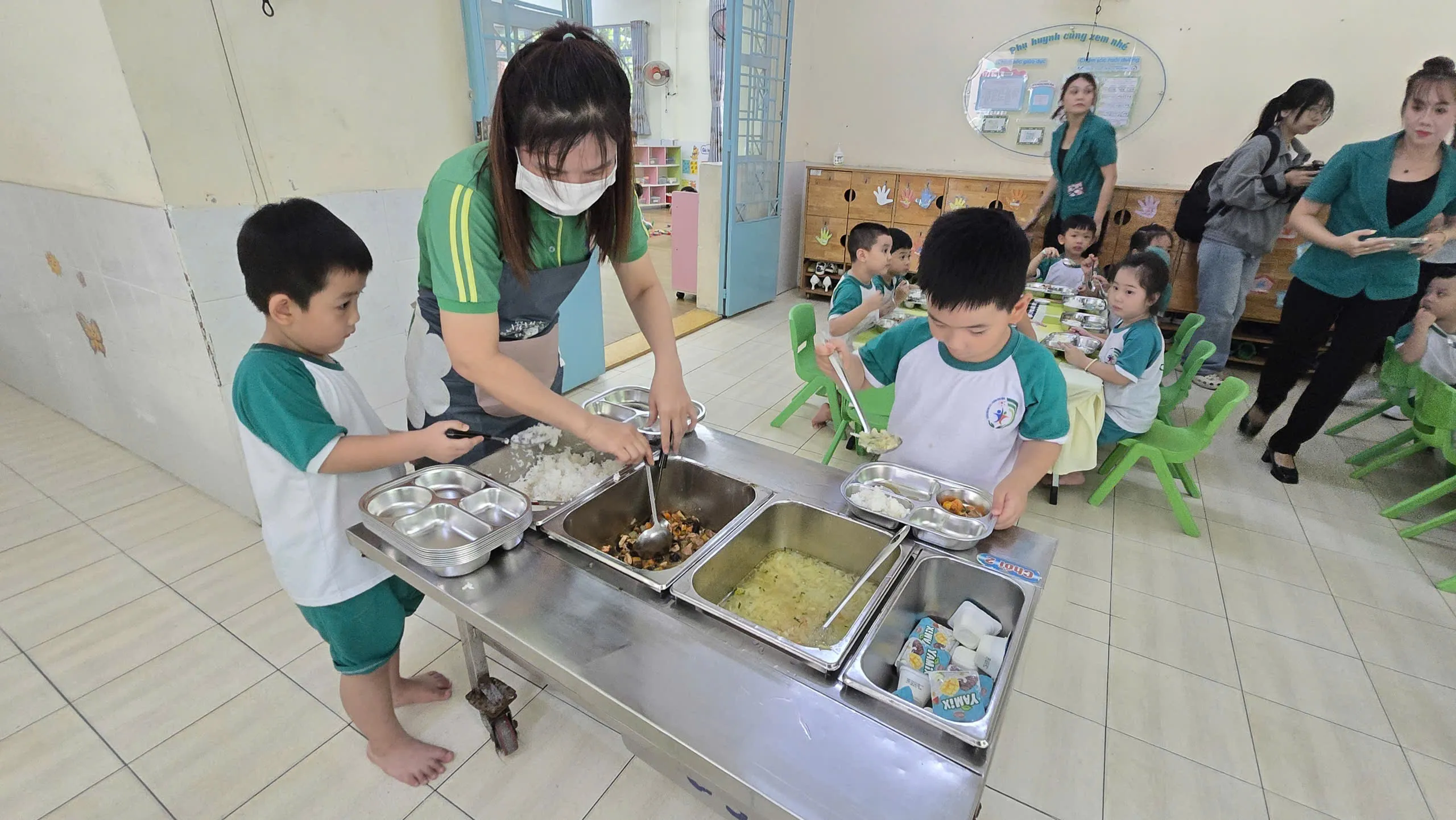 Trẻ mầm non tự múc các món ăn tại bữa trưa ở Trường Mầm non 19 tháng 5 với thực phẩm trong mô hình %22Tick xanh trách nhiệm%22 - Ảnh Bá Nam