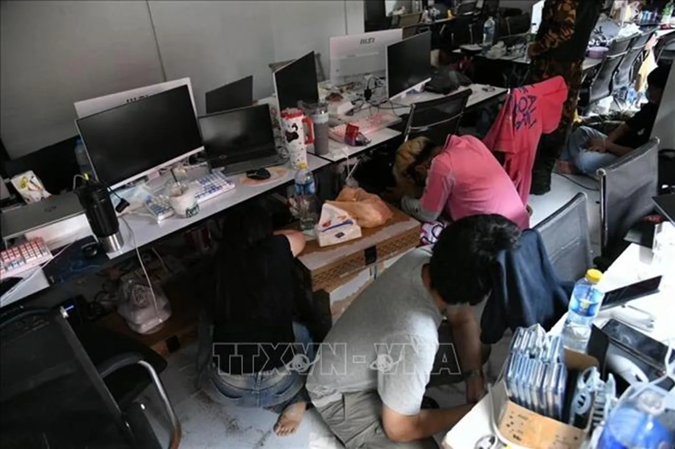 Các đối tượng bị khống chế tại vị trí làm việc cùng hệ thống máy tính dùng để vận hành các trang web cờ bạc và lừa đảo trực tuyến - Ảnh: TTXVN