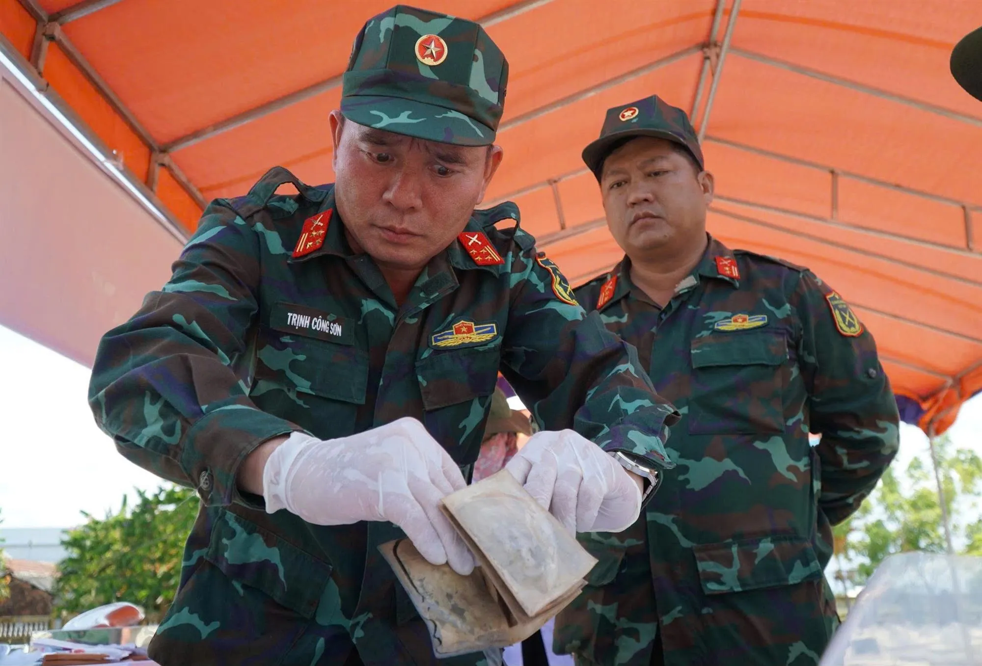Đại tá Trịnh Công Sơn mắt đỏ hoe và cẩn thận đến mức căng thẳng khi bóc tách chiếc ví - Ảnh: Trần Mai - TTO
