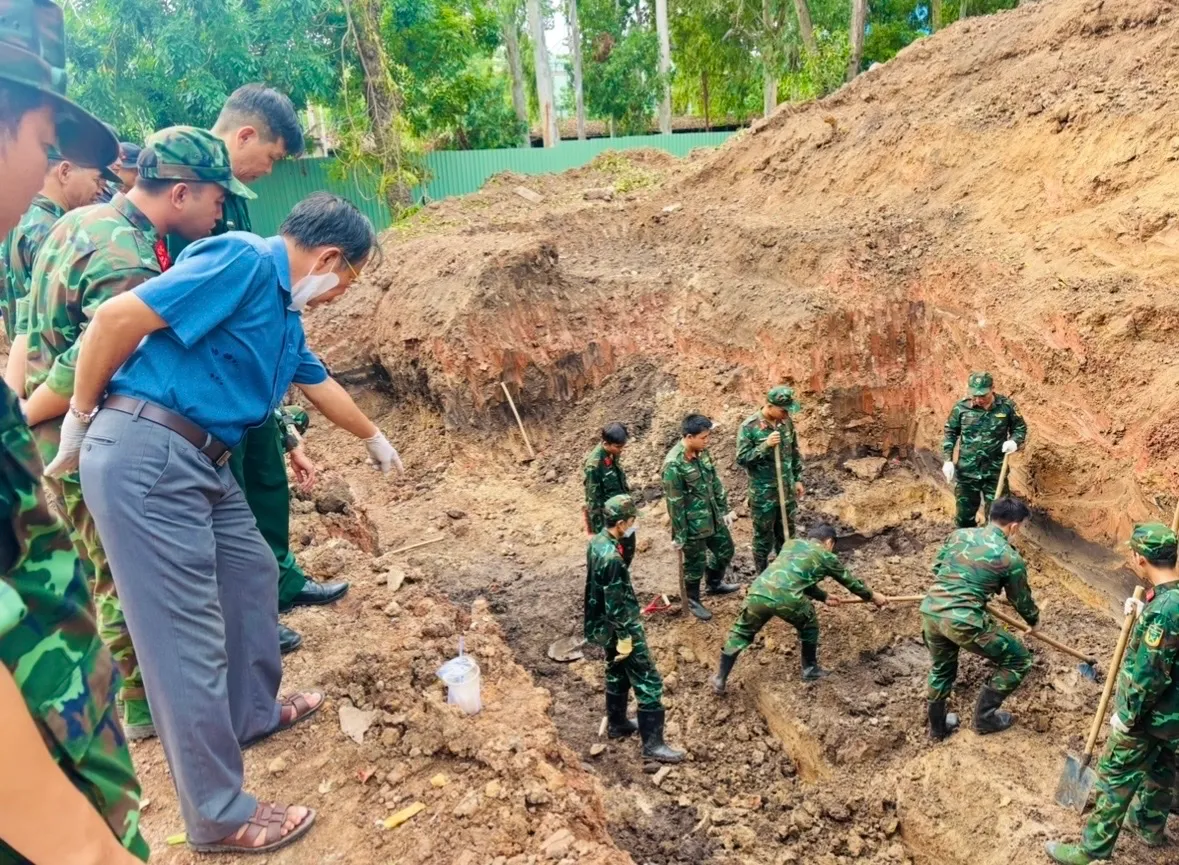 Bác sĩ Trần Văn Bản hướng dẫn các chiến sĩ trẻ thao tác lấy hài cốt lên khỏi mặt đất - Ảnh: Thủy Tiên