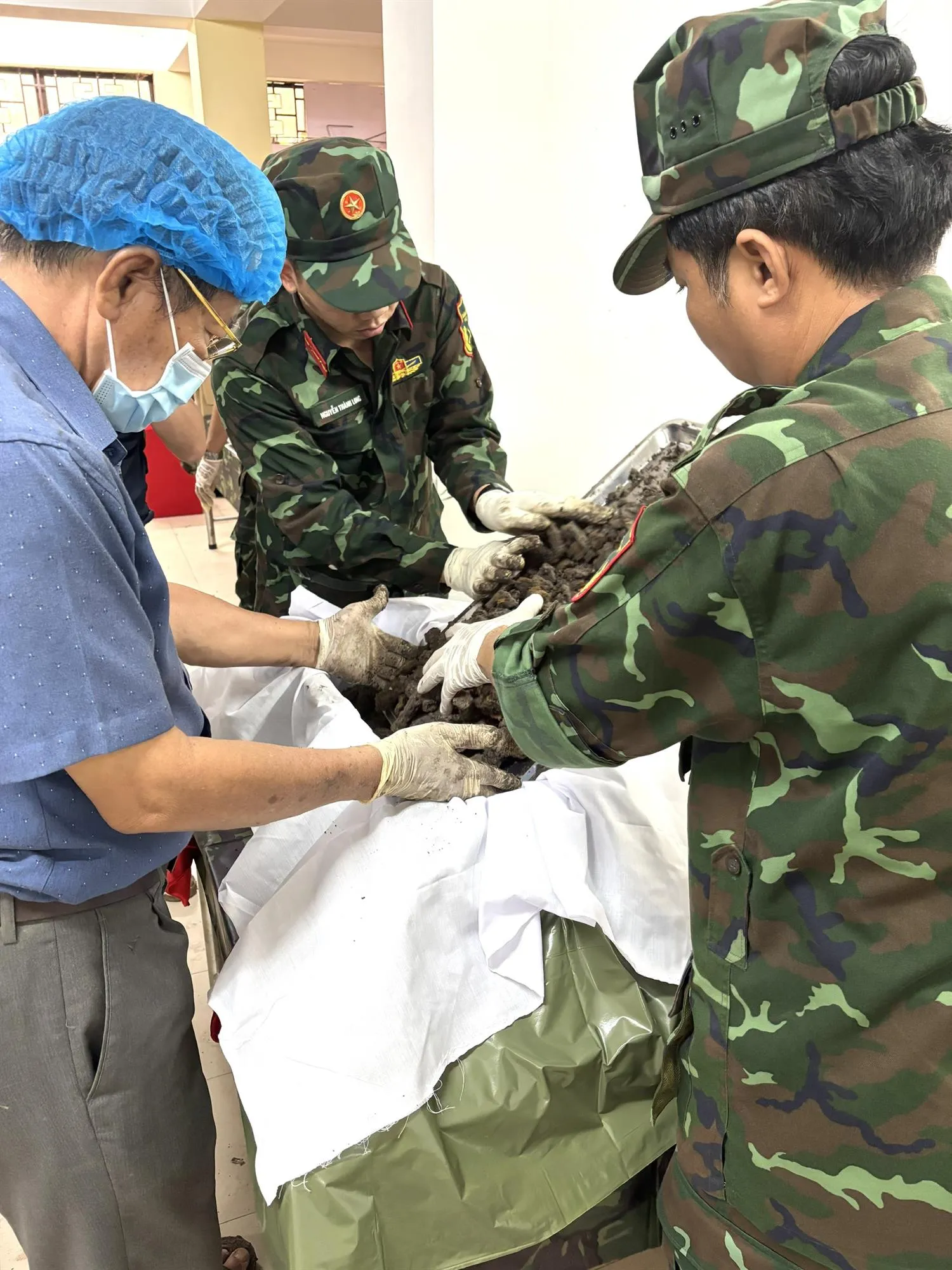 Bác sĩ Trần Văn Bản cùng các chiến sĩ K71 hoàn tất quy trình đưa hài cốt liệt sĩ vào phòng chờ giám định - Ảnh: Thủy Tiên