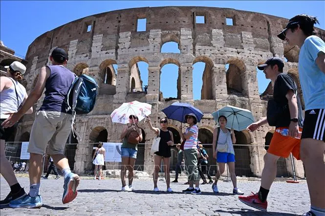Khách du lịch che ô tránh nắng nóng khi tham quan Đấu trường La Mã ở Rome, Italy. Ảnh: THX/TTXVN