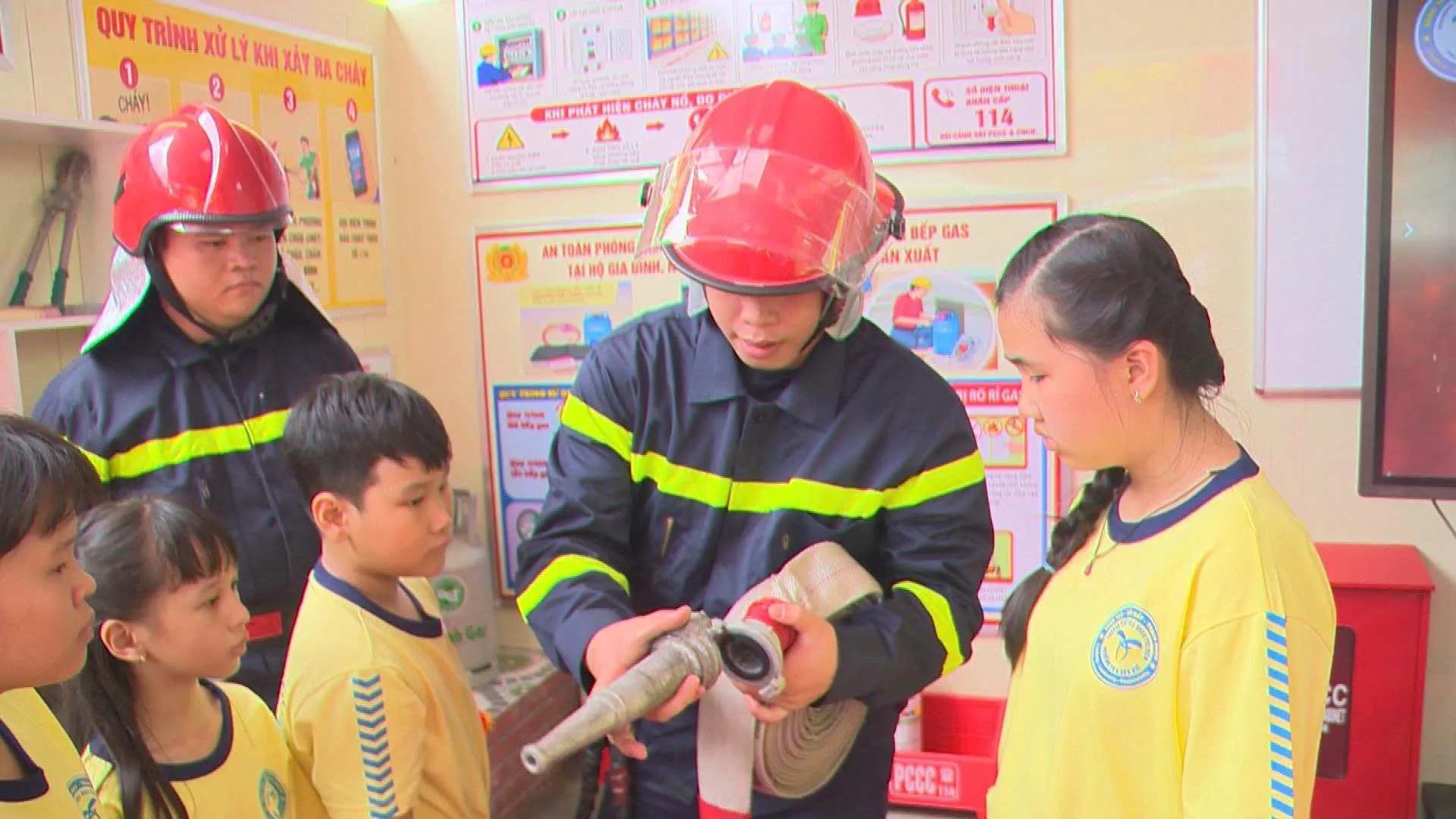 Học sinh chăm chú lắng nghe và quan sát cán bộ PCCC hướng dẫn cách sử dụng vòi chữa cháy và các phương tiện dập lửa ban đầu