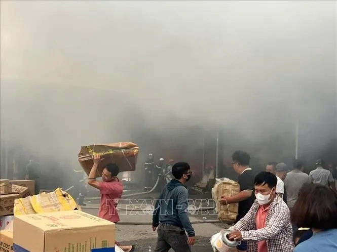 Người dân di chuyển đồ đạc khỏi khu vực xảy ra cháy. Ảnh: Phạm Kiên - TTXVN