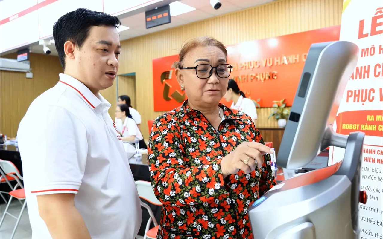 Ông Phạm Trần Tuấn Khải, Giám đốc Trung tâm Phục vụ hành chính công phường Minh Phụng, hướng dẫn người dân trải nghiệm Robot hành chính công và Chatbot AI