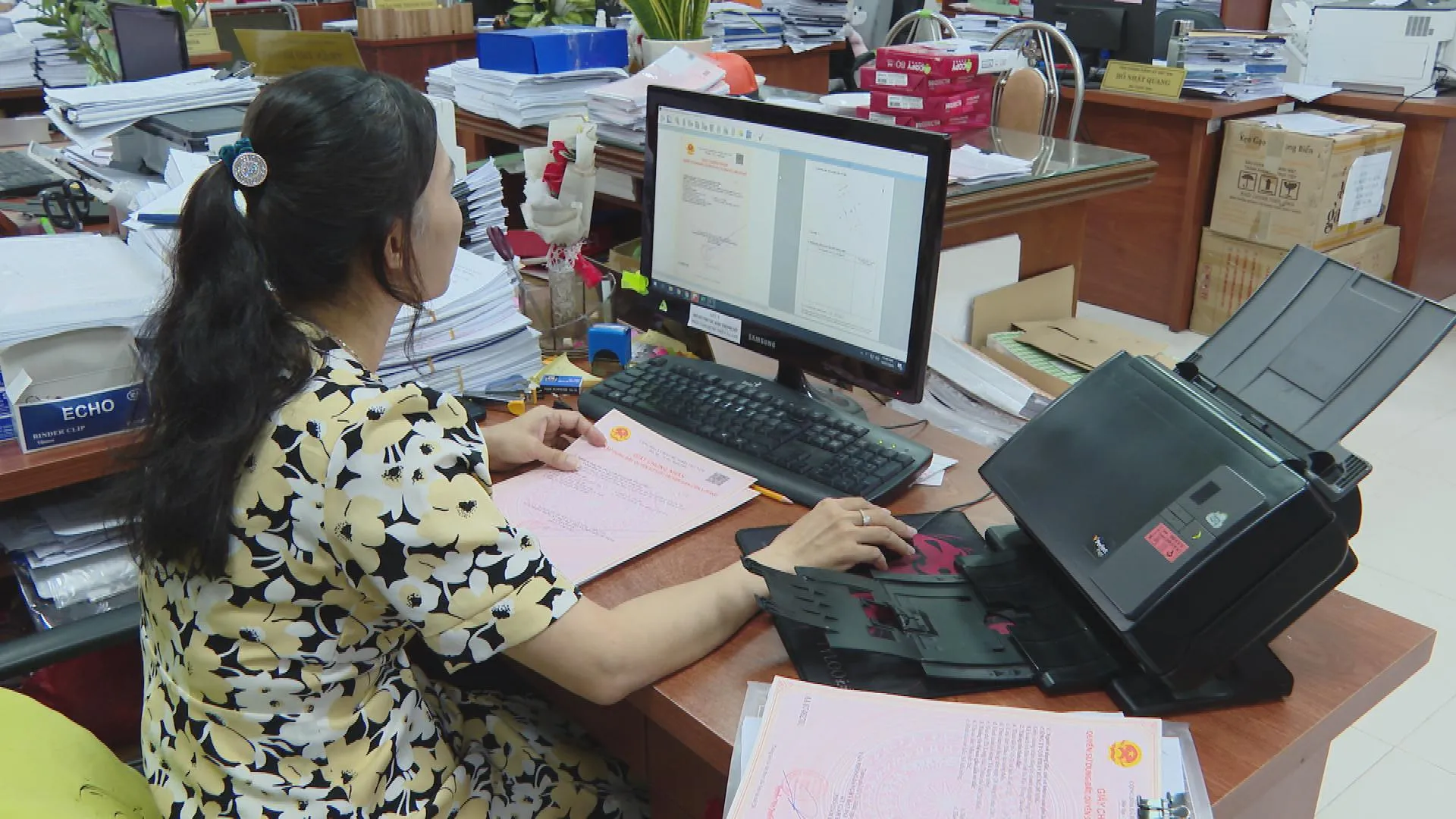 Cán bộ Văn phòng Đăng ký đất đai thực hiện quy trình quét hồ sơ và hoàn thiện giấy chứng nhận cho người dân