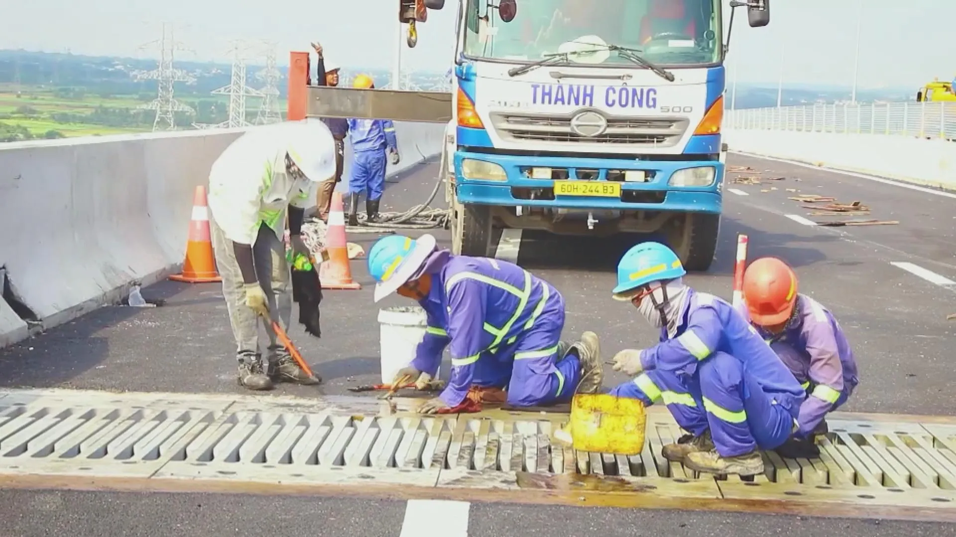 Đội ngũ công nhân đang thi công và hoàn thiện hệ thống rãnh thoát nước trên cầu