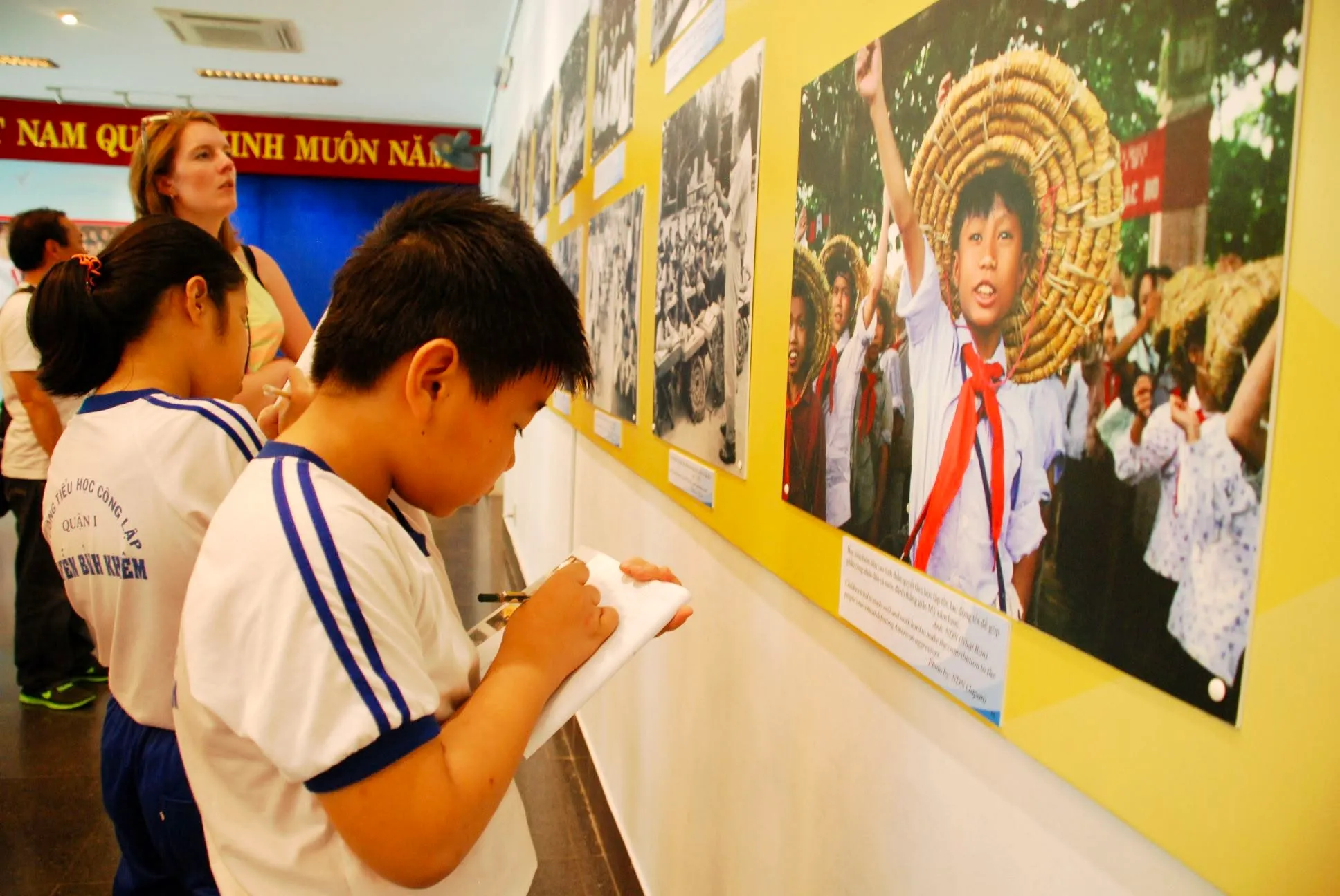 Các em học sinh trường Tiểu học Nguyễn Bỉnh Khiêm ghi chép thông tin khi tham quan triển lãm chuyên đề “Trẻ em thời chiến”