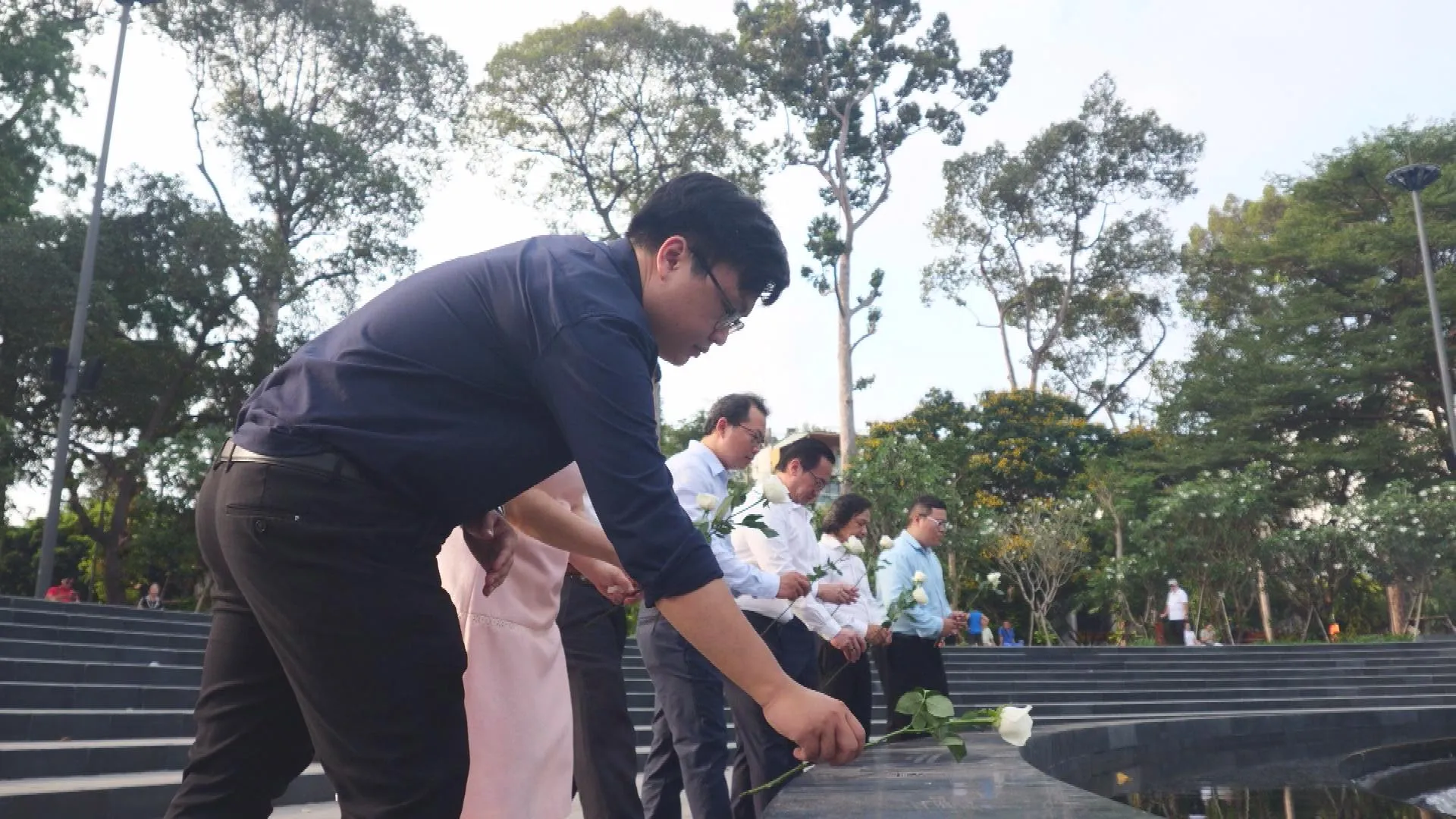 Các đại biểu và lực lượng tuyến đầu trang nghiêm cầm hoa cúc trắng chuẩn bị dâng lên đài tưởng niệm-h2
