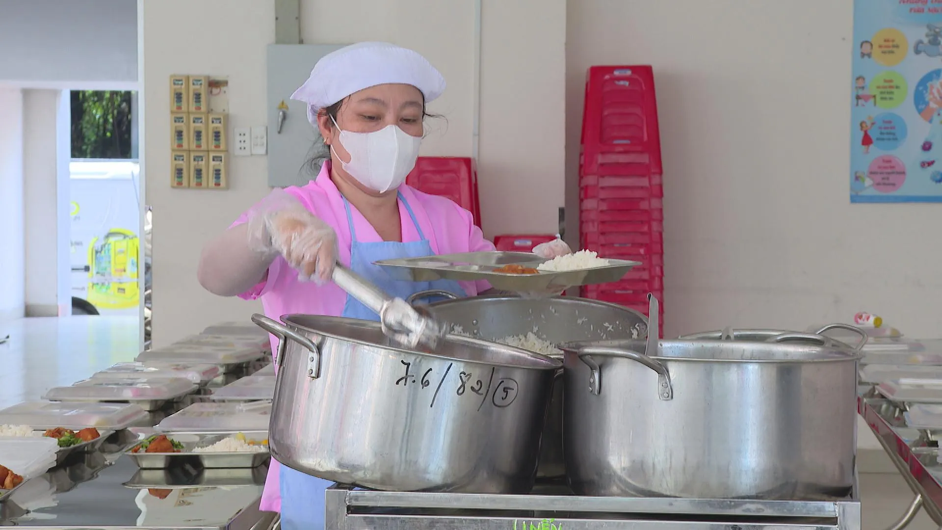 Nhân viên nhà bếp chuẩn bị và chia suất ăn cho học sinh tại trường; các món ăn được chuẩn bị theo suất phục vụ học sinh bán trú