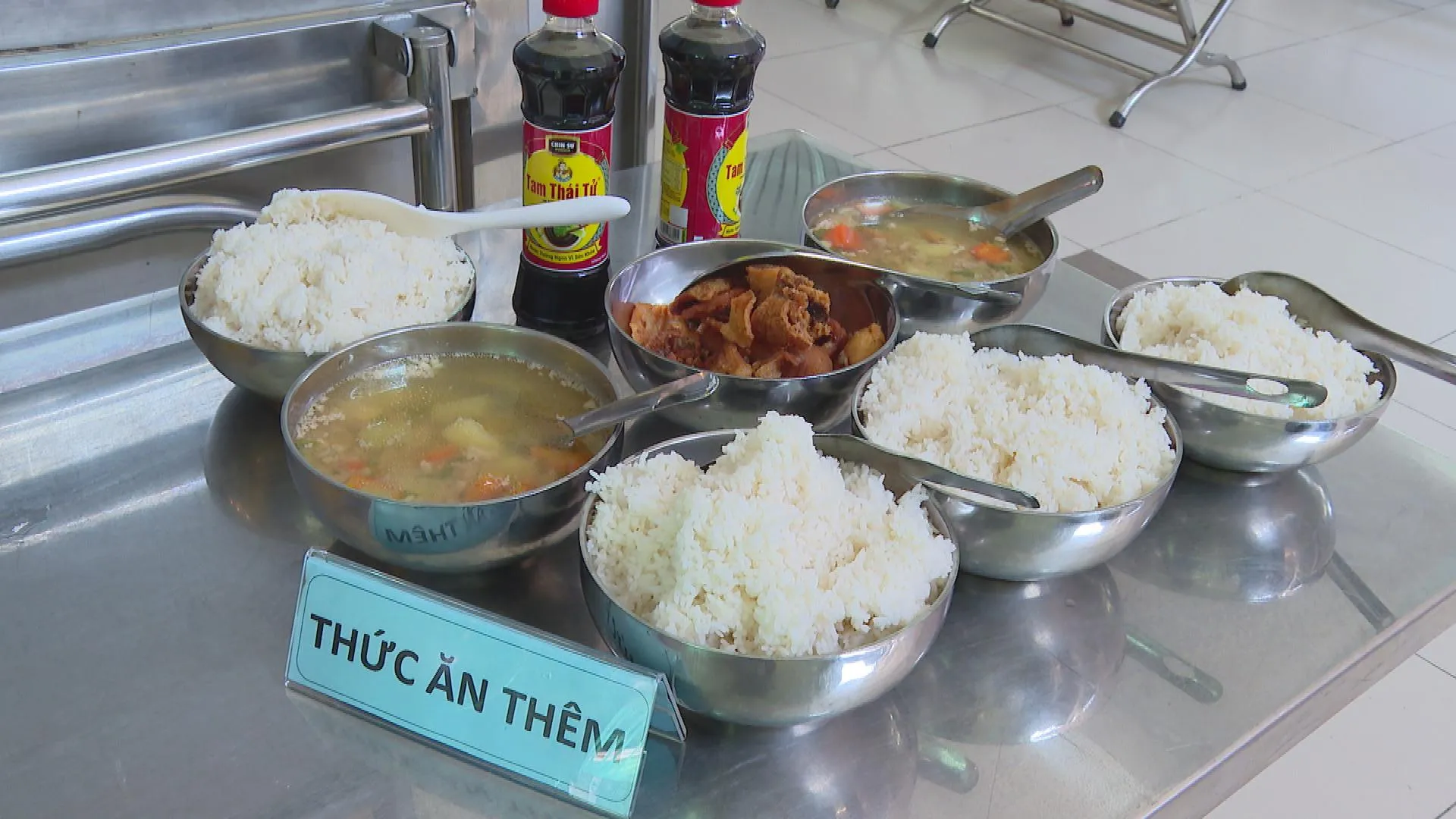 Nhân viên nhà bếp chuẩn bị và chia suất ăn cho học sinh tại trường; các món ăn được chuẩn bị theo suất phục vụ học sinh bán trú
