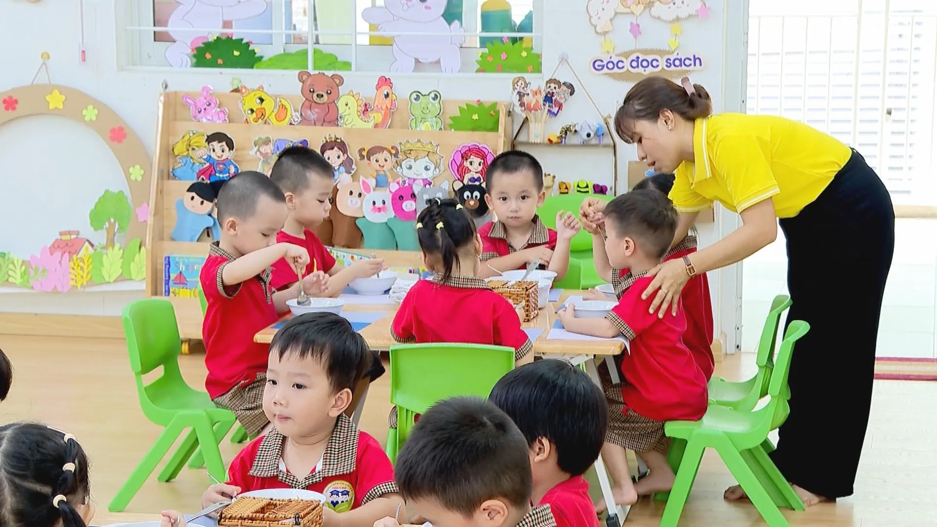 Giáo viên hướng dẫn trẻ dùng bữa tại trường mầm non trong giờ ăn bán trú