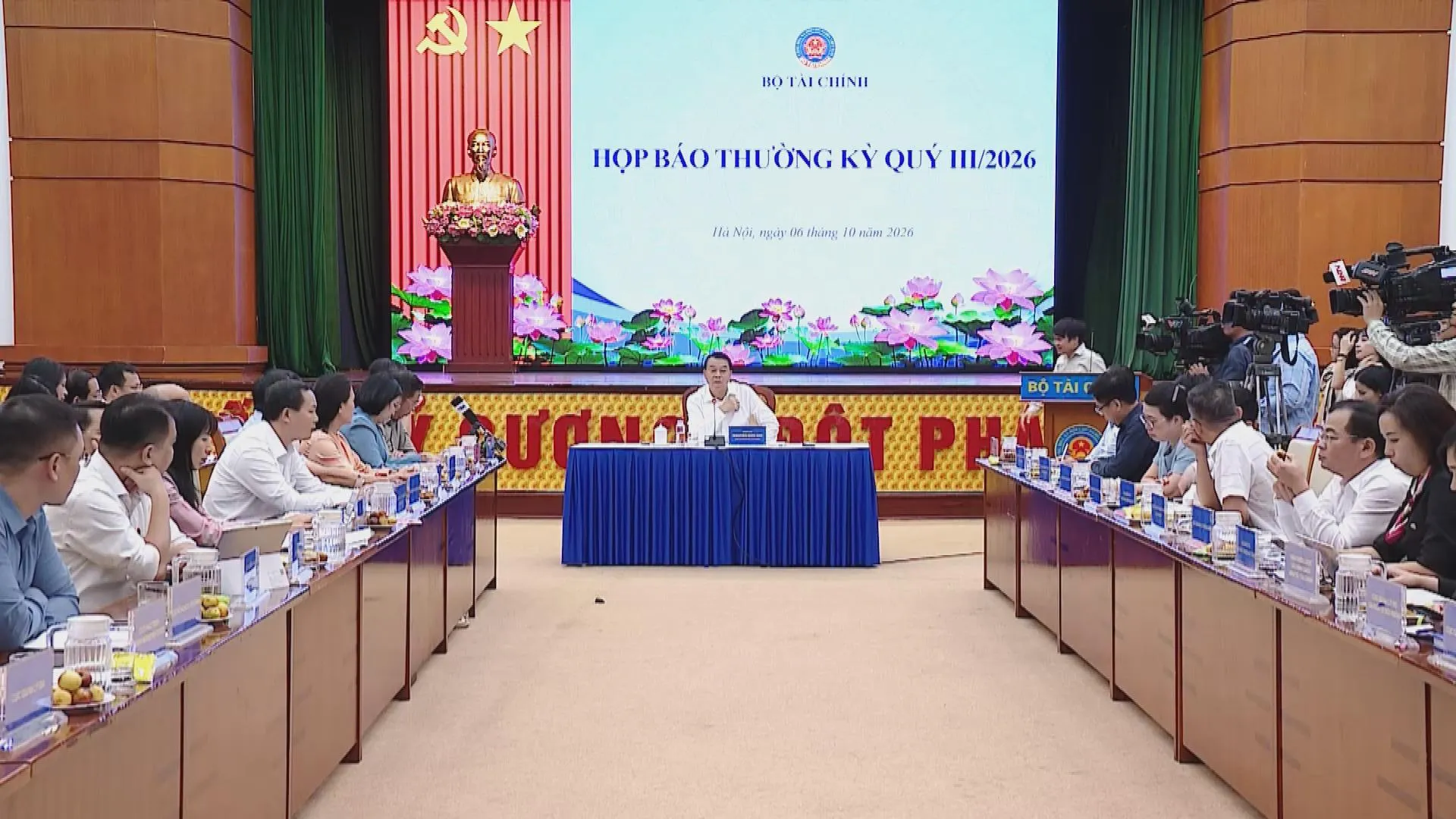 Hội trường họp báo Bộ Tài chính với đại diện chủ trì và các đơn vị ngồi dọc hai dãy bàn hội nghị - Ảnh 1.