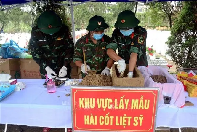 Lấy mãu hài cốt liệt sĩ tại nghĩa trang Liệt sĩ Hàm Rồng - Ảnh: TTXVN
