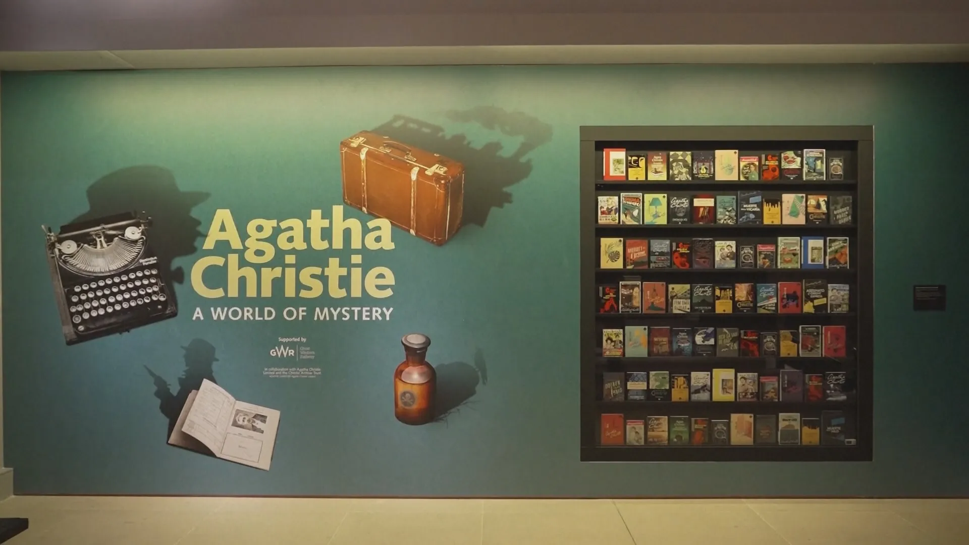 Triển lãm về nữ hoàng tiểu thuyết trinh thám Agatha Christie - Ảnh 1. Bức tường chào mừng tại Thư viện Anh hiển thị tên triển lãm "Agatha Christie: A World of Mystery" bên cạnh chiếc máy đánh chữ quen thuộc và kệ trưng bày hàng loạt tựa sách trinh thám xuất sắc của bà
