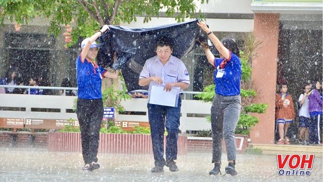 Sinh viên tình nguyện che cho thí sinh khỏi ướt ngày làm thủ tục dự thi